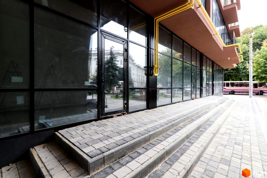 Зовнішній вигляд новобудови ЖК Central House з панорамними вікнами та сходами, що ведуть до входу. Прибудинкова територія вимощена плиткою.