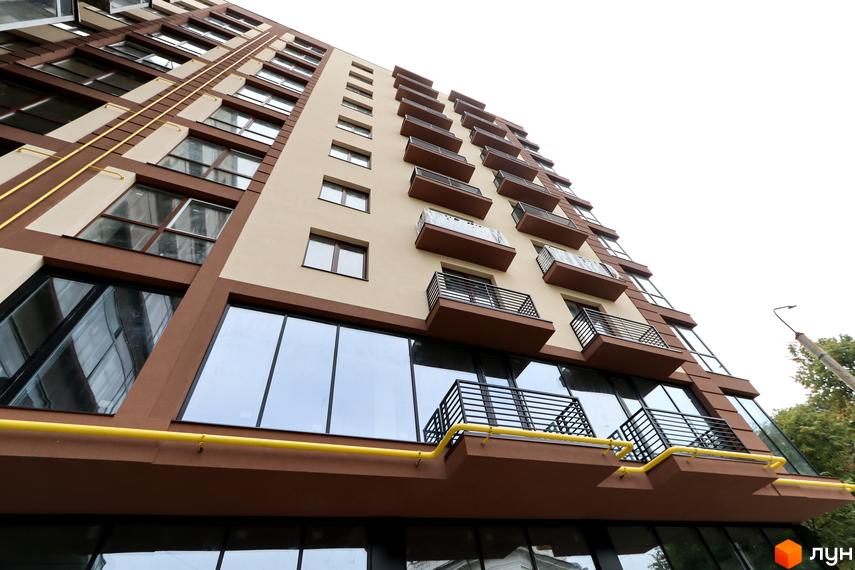 Фасад житлового комплексу Central House з коричневими та бежевими елементами, балконами та великими вікнами. Вид знизу на будівлю.