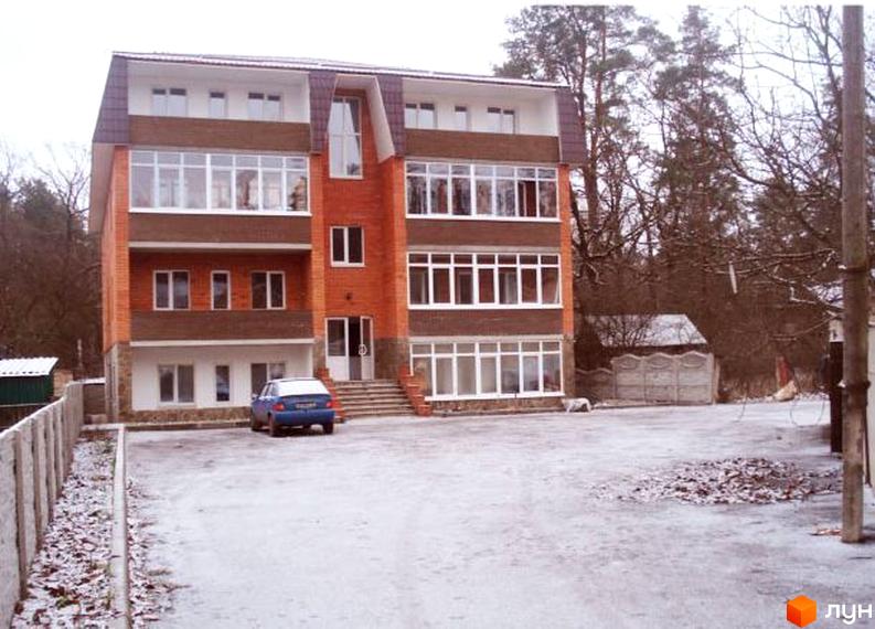 Чотириповерхова цегляна новобудова за адресою вул. Київська, 45в з білими вікнами. Перед будинком засніжена територія та припаркований синій автомобіль.