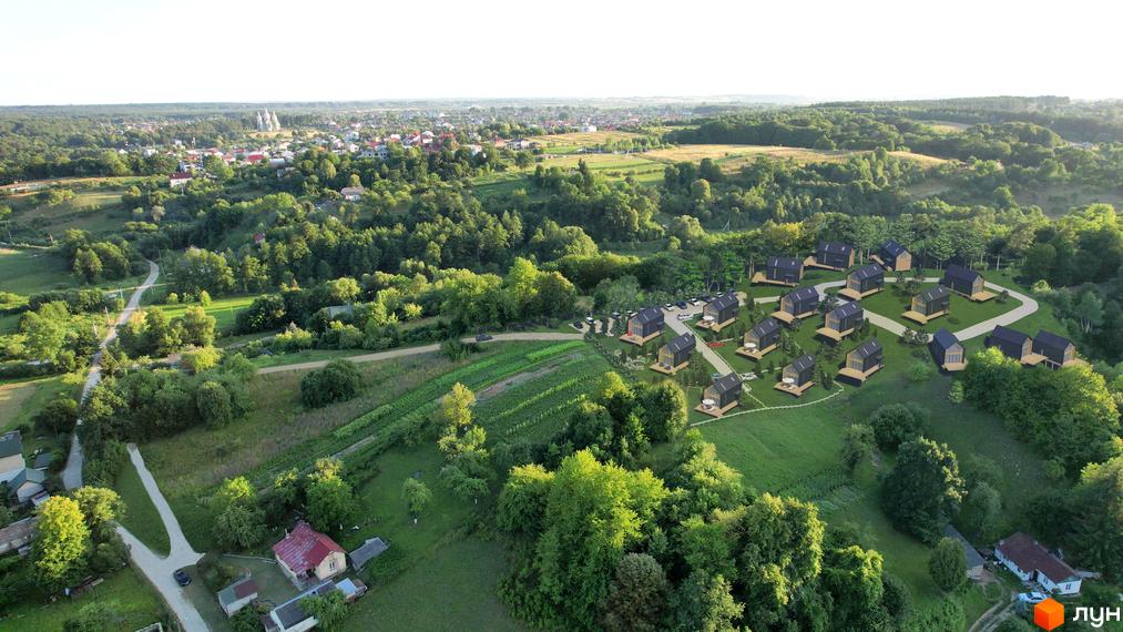 Котеджне містечко КМ Схили: сучасні будинки з темними фасадами та дерев'яними елементами розташовані на схилі пагорба серед зелені.