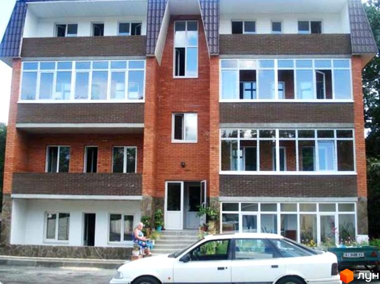 Житловий комплекс на вул. Київська, 45в, з червоною цеглою та великими вікнами. Прибудинкова територія з автомобілем та зеленими насадженнями.