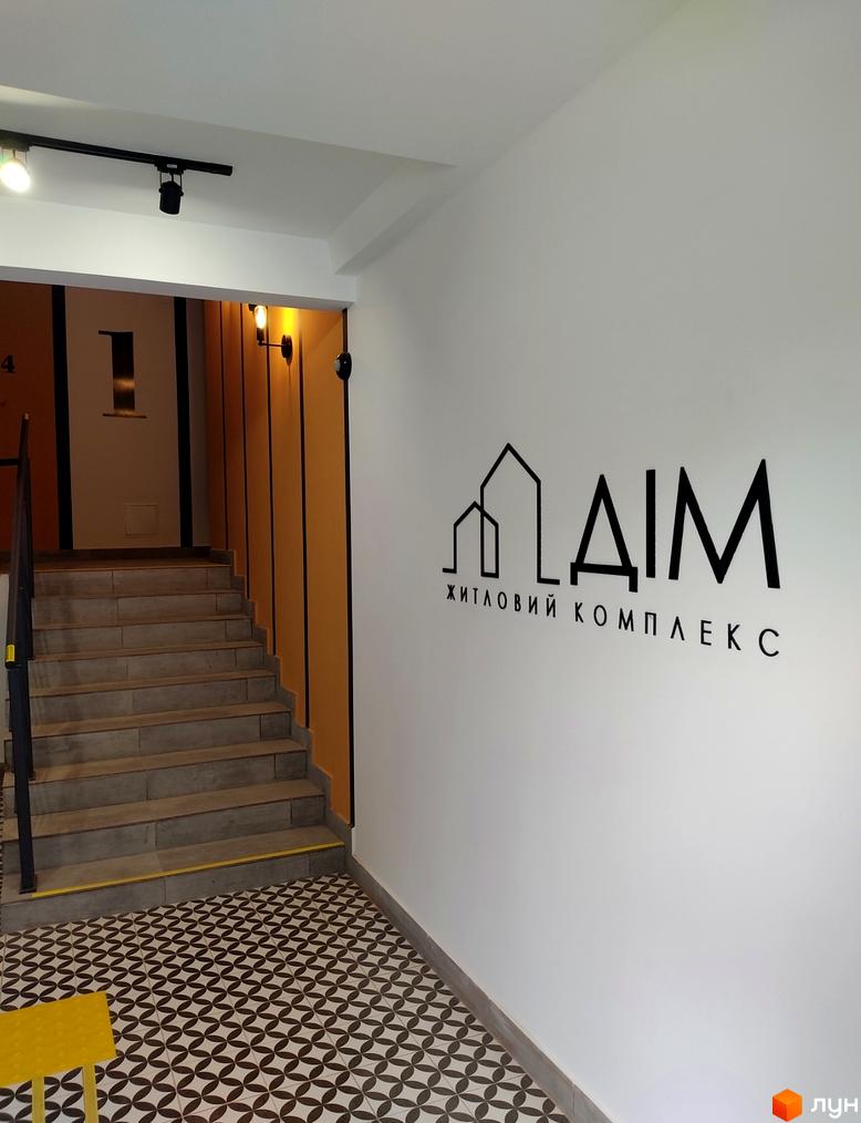 Вхідна група Житлового комплексу Дім. Інтер'єр з багатоступеневими сходами, візерунковою підлогою та освітленням.