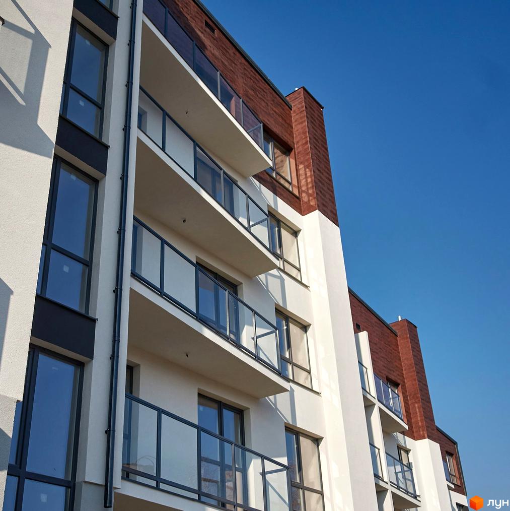 Фасад житлового комплексу Традиція з балконами та вікнами на тлі блакитного неба. Сучасна архітектура новобудови.