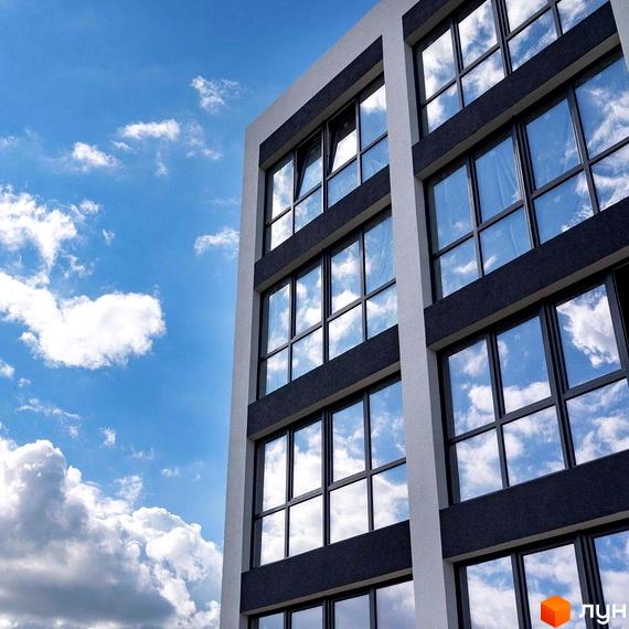 Зовнішній вигляд житлового комплексу Традиція з великими вікнами, що відбивають блакитне небо з хмарами. Фасад будівлі виконаний у сірих та білих тонах.