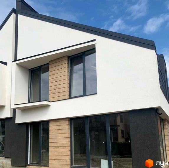 Фасад будинку Atlant House з білою штукатуркою, дерев'яними елементами та великими вікнами. Зовнішній вигляд новобудови.