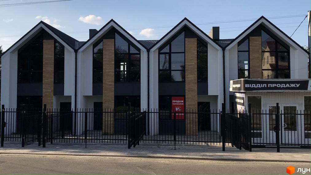 Сучасні таунхауси Well Home з великими вікнами та акуратним фасадом, огороджені чорним парканом.