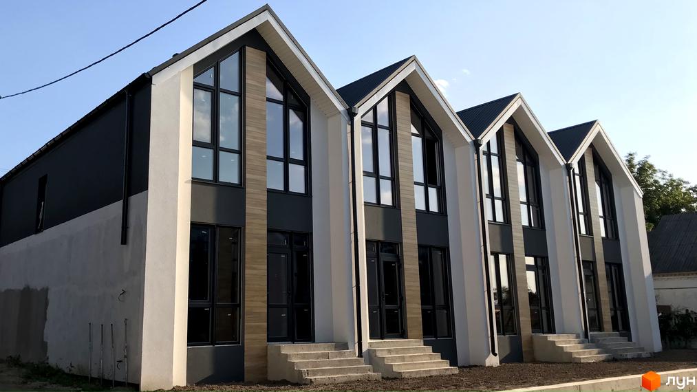 Зображення таунхаусів Well Home з великими вікнами та сходами до входу. Фасад оздоблений у світлих та темних тонах.