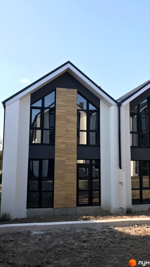 Зовнішній вигляд таунхаусу Well Home. Двоповерховий будинок з великими вікнами та оздобленням під дерево.