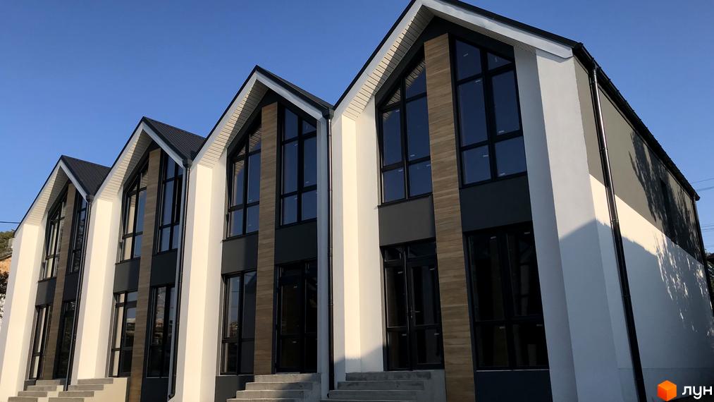 Зображення таунхаусів Well Home з великими вікнами та темним дахом. Світлі стіни та сірі вставки в оздобленні фасадів.