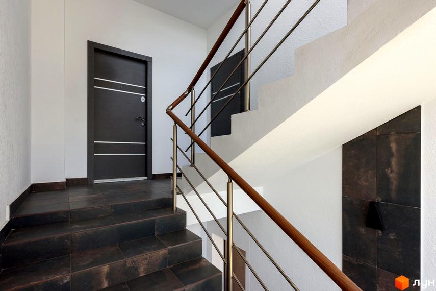 Сходи в під'їзді Житлового комплексу Elite House з металевими поручнями та темними плитками на підлозі.