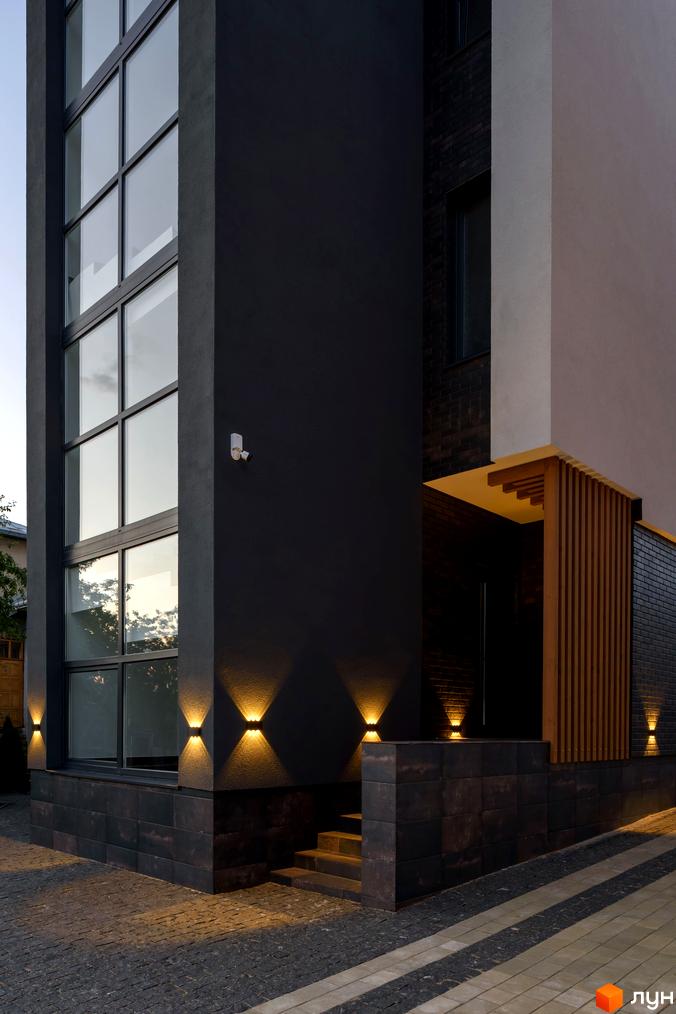 Зовнішній вигляд будинку в Житловому комплексі Elite House з великими вікнами та підсвічуванням. Вигляд на фасад та частину подвір'я.