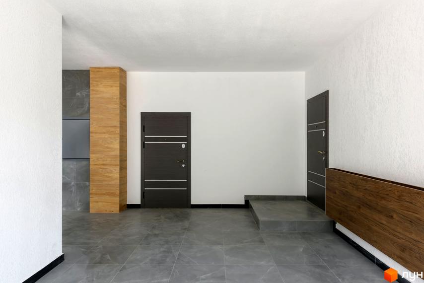 Передпокій у новобудові ЖК Center з темними дверима та сірою плиткою на підлозі. Інтер'єр з дерев'яними елементами та білими стінами.