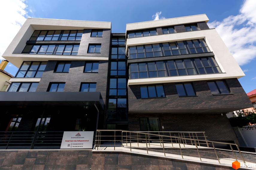 Фасад житлового комплексу Center з цегляним облицюванням та великими вікнами. Поруч розташована прибудинкова територія з пандусом.