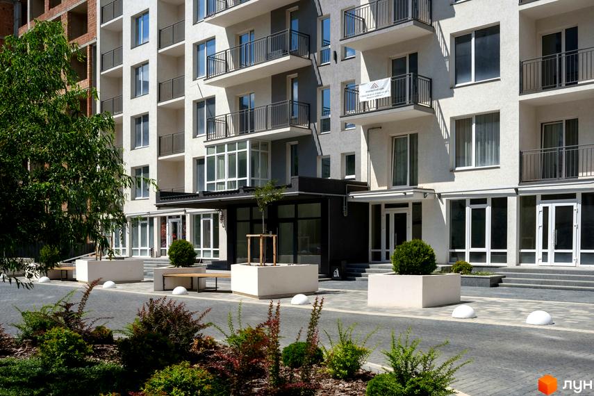Зовнішній вигляд Новобудови KromaxBud з балконами та великими вікнами. На передньому плані прибудинкова територія з ландшафтним дизайном.