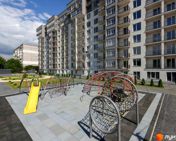 Новобудова ЖК KromaxBud з дитячим майданчиком та гіркою. Сучасний житловий комплекс з упорядкованою прибудинковою територією.