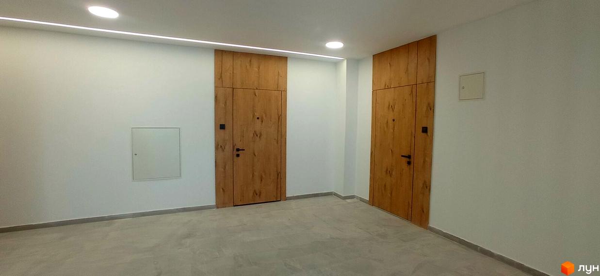 Дизайн холу житлового комплексу Rubicon Premium з дерев'яними дверима та прихованими люками. Сучасний інтер'єр з мінімалістичним освітленням.