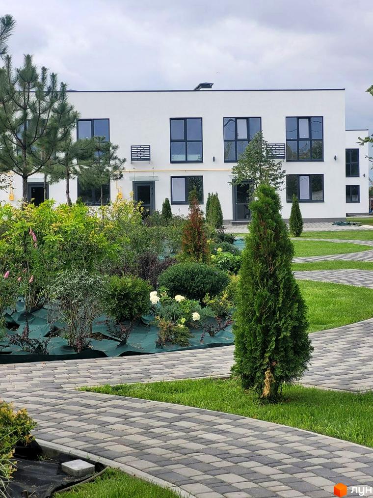 Зовнішній вигляд DREAM HOUSE: біла будівля з темними вікнами та доглянута прибудинкова територія з рослинністю і доріжками.