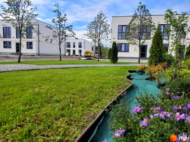 Зовнішній вигляд будинків DREAM HOUSE з прибудинковою територією, газоном та квітами. Сучасна архітектура та доглянутий ландшафт.