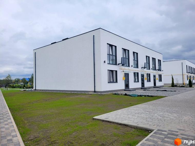 Таунхауси DREAM HOUSE з білими фасадами та темними вікнами, розташовані на доглянутій території з бруківкою та газоном.