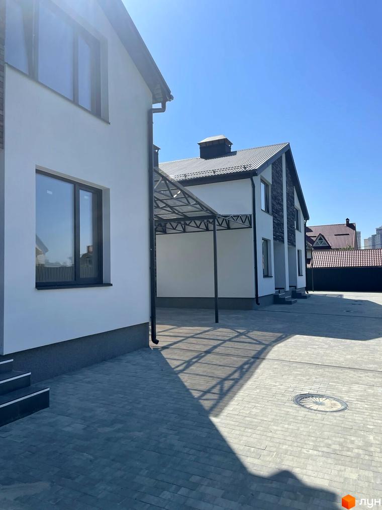 Дуплекси „На Драгоманова“: фасади будинків білого кольору з елементами темного каменю, прибудинкова територія вимощена плиткою.