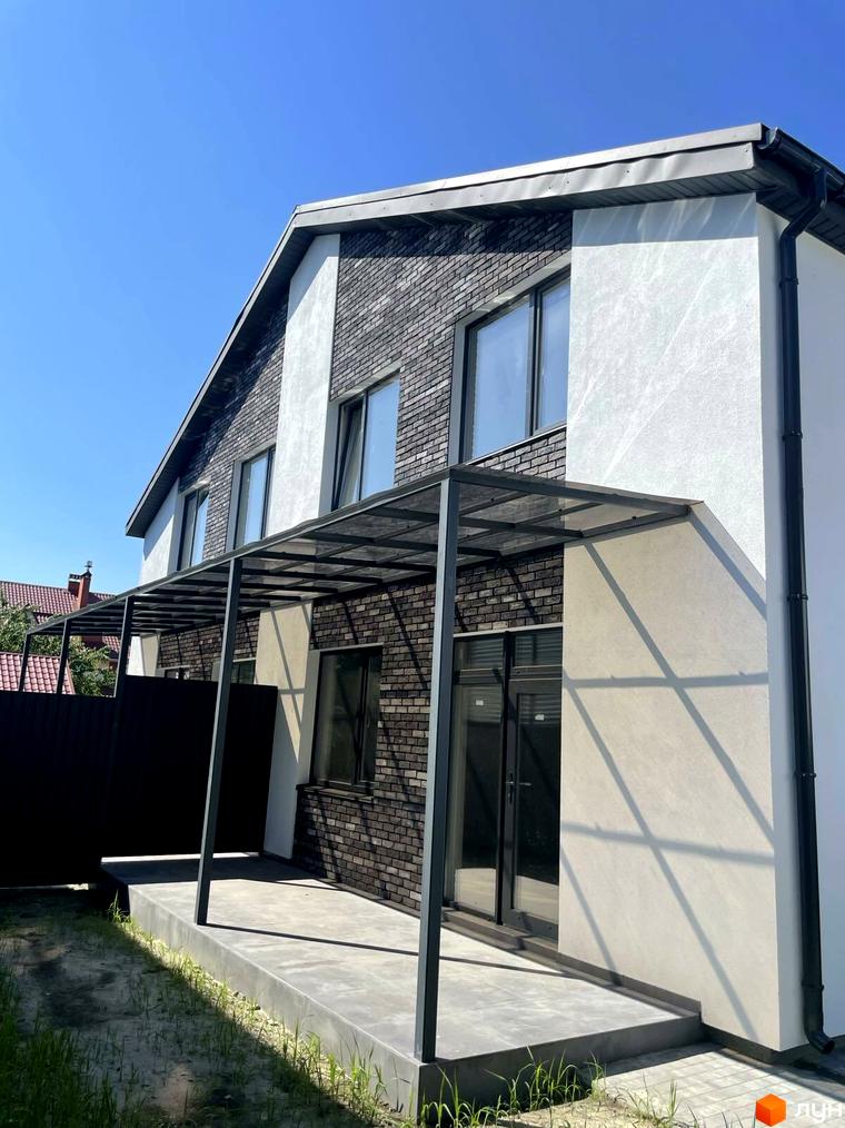 Дуплекси „На Драгоманова“: двоповерхові будинки з цегляним фасадом та навісом біля входу. Територія перед будинком вимощена плиткою та засаджена травою.