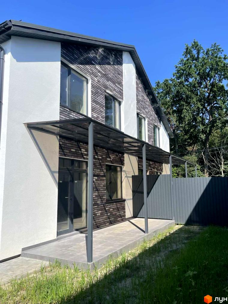 Зовнішній вигляд дуплексів „На Драгоманова“ з цегляним фасадом та терасою. Прибудинкова територія з зеленим газоном та парканом.