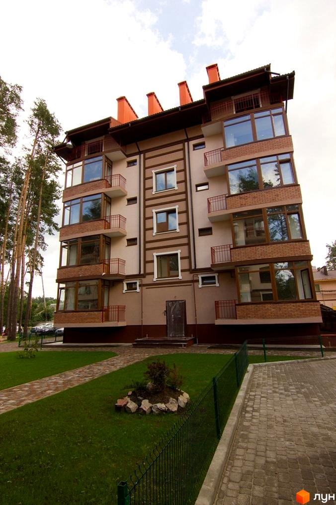 Житловий комплекс ЖК Жемчужина з сучасним фасадом та великими вікнами. Прибудинкова територія з газоном та пішохідними доріжками.