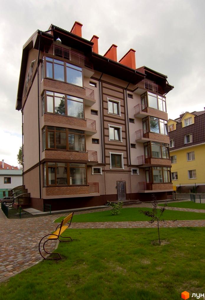 Житловий комплекс ЖК Жемчужина з фасадом, великими вікнами та прибудинковою територією з газоном і доріжками.