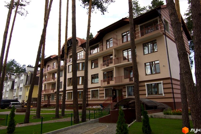 Житловий комплекс Жемчужина города: багатоповерховий будинок з балконами та вікнами, оточений деревами. Прибудинкова територія з доріжками та зеленню.