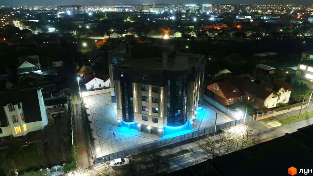 Зображення сторінки ЖК на вул. Коперника, 83. Багатоповерховий будинок з скляними фасадами та підсвіткою, навколо будинку бруківка та освітлення.