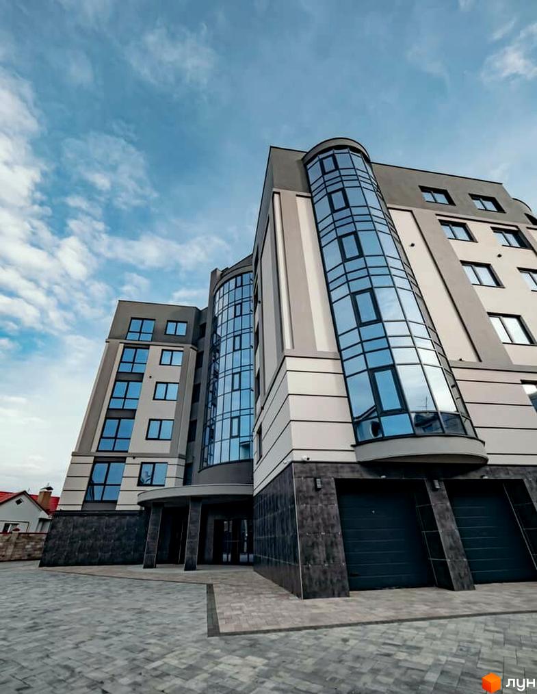 Зображення фасаду будинку на вулиці Коперника, 83. На фото видно багатоквартирний будинок з панорамними вікнами та облаштований тротуар.