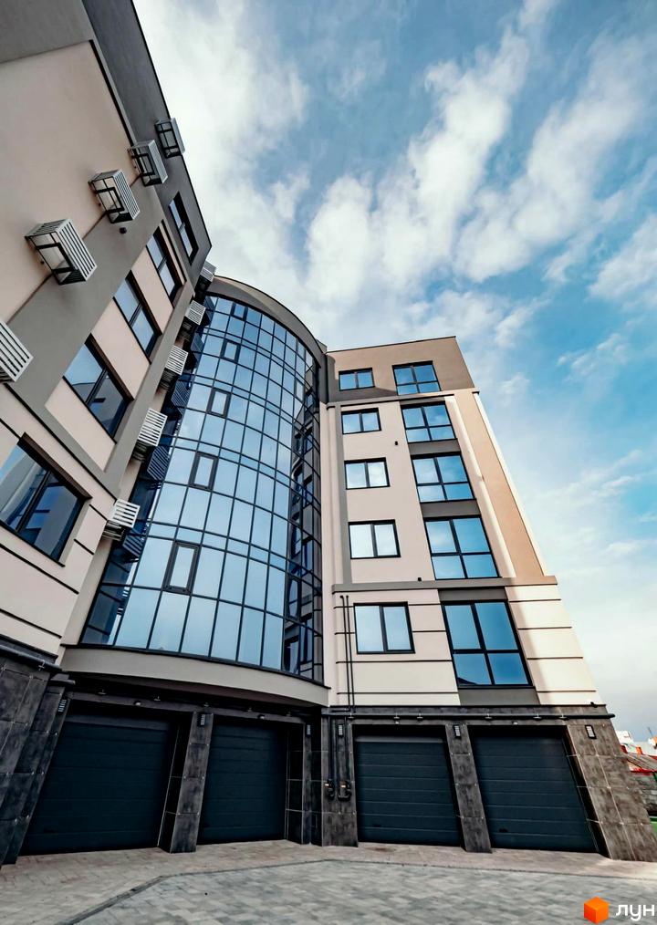 Зовнішній вигляд будинку на вулиці Коперника, 83. Фасад будівлі з великими вікнами та гаражними воротами, на фоні блакитного неба.