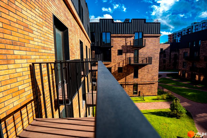 Вид на цегляні будинки клубного містечка 12 з балкона. Прибудинкова територія з газоном та доріжками.