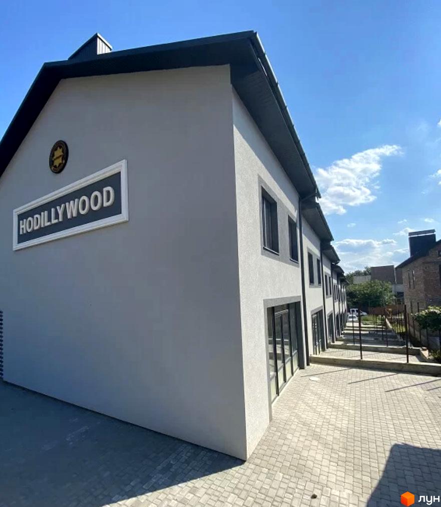 Зовнішній вигляд таунхаусів Hodillywood 3.0 з сірим фасадом та темним дахом. Поруч розташована вимощена бруківкою прибудинкова територія.