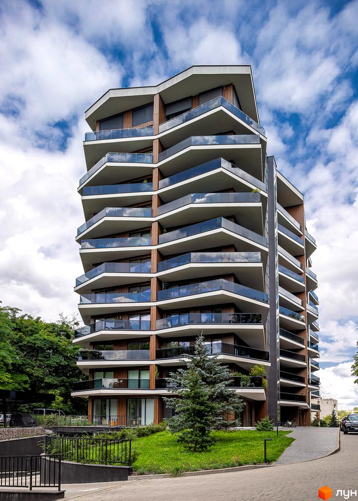 Житловий комплекс Avalon Lux з багатоповерховими балконами та скляними перилами. Прибудинкова територія з зеленими насадженнями та доріжками.