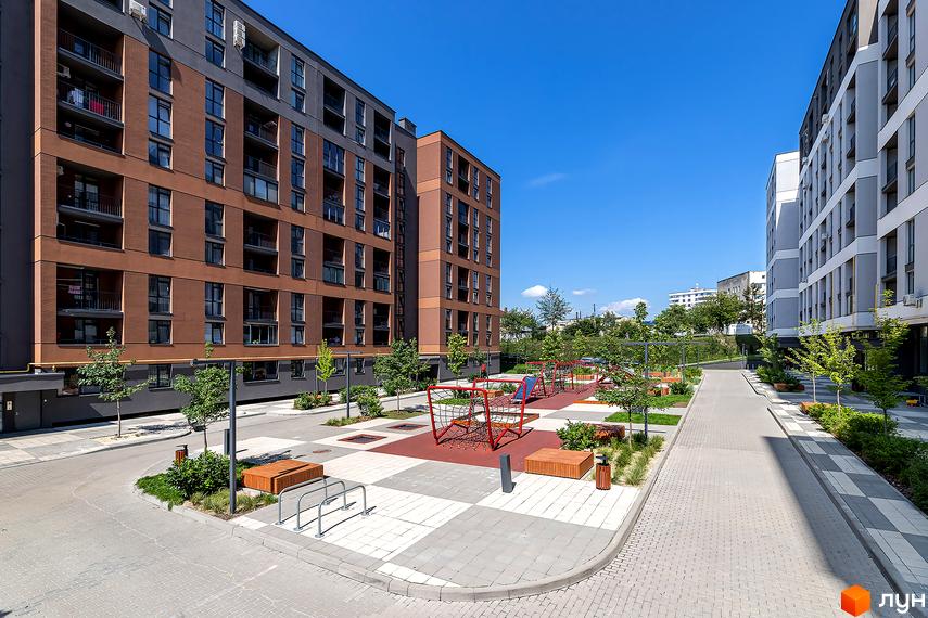Вигляд житлового району Avalon Zelena Street з багатоповерховими будинками та дитячим майданчиком у дворі. Облаштована прибудинкова територія.