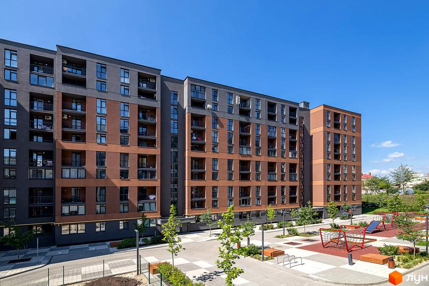 Зовнішній вигляд Житлового комплексу Avalon Zelena Street. Багатоповерховий будинок з коричневим фасадом та великими вікнами, поруч дитячий майданчик.