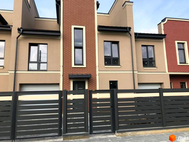 Фасад таунхаусів „Преміум“ з великими вікнами та парканом з ламелями. Житловий комплекс з сучасними будинками та доглянутою прибудинковою територією.