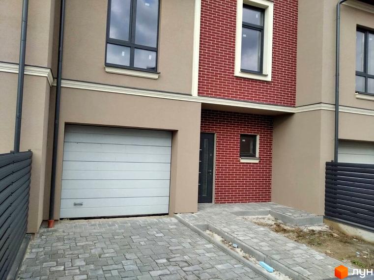 Зовнішній вигляд таунхаусу в Будівельний проєкт „Преміум“ з фасадом з цегли та гаражем. Бруківка на прибудинковій території.
