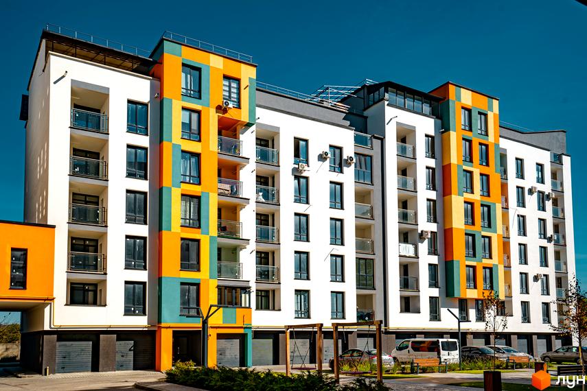 Житловий комплекс Квартал Краківський з яскравим фасадом та балконами. На прибудинковій території розташовані дитячі гойдалки та парковка.