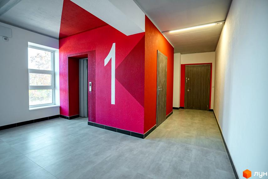 Житловий комплекс Квартал Краківський. Сучасний вхід в будинок з ліфтом та дверима, оформлений в червоних тонах, з великою цифрою 1.