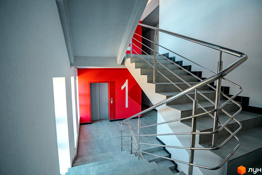 Сходи та ліфт у житловому комплексі Квартал Краківський. Сучасний дизайн під'їзду з яскравим червоним акцентом та порядковим номером поверху.