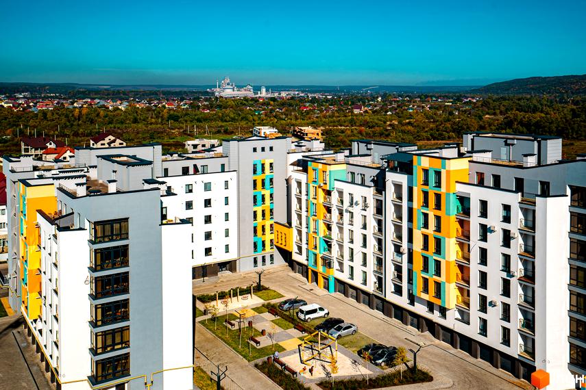 Житловий комплекс Квартал Краківський з яскравими фасадами та прибудинковою територією з дитячим майданчиком та парковкою. Вид зверху на новобудову.