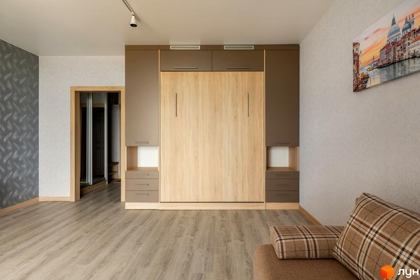 Сучасний житловий комплекс Арден Курортний з вбудованими шафами та ліжком, що трансформується. Простора кімната з дерев'яною підлогою та картиною на стіні.