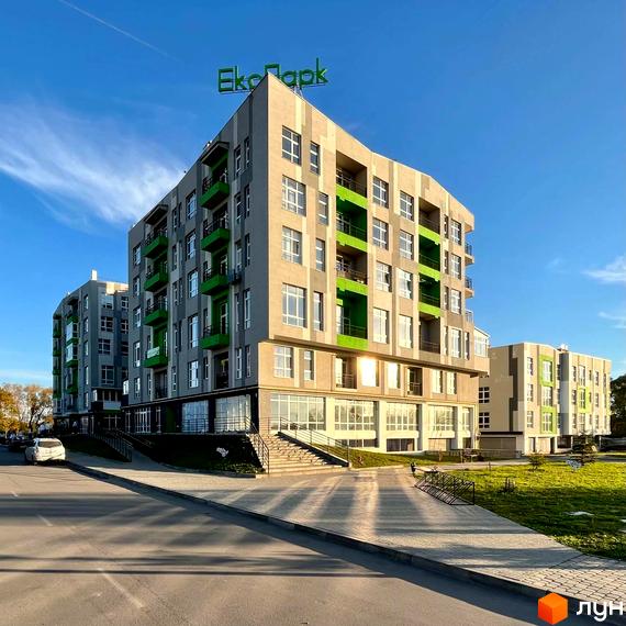 Новобудова ЖК ЕкоПарк з сірими фасадами та яскраво-зеленими балконами. Навколо будівлі доглянута прибудинкова територія з газоном та пішохідними доріжками.