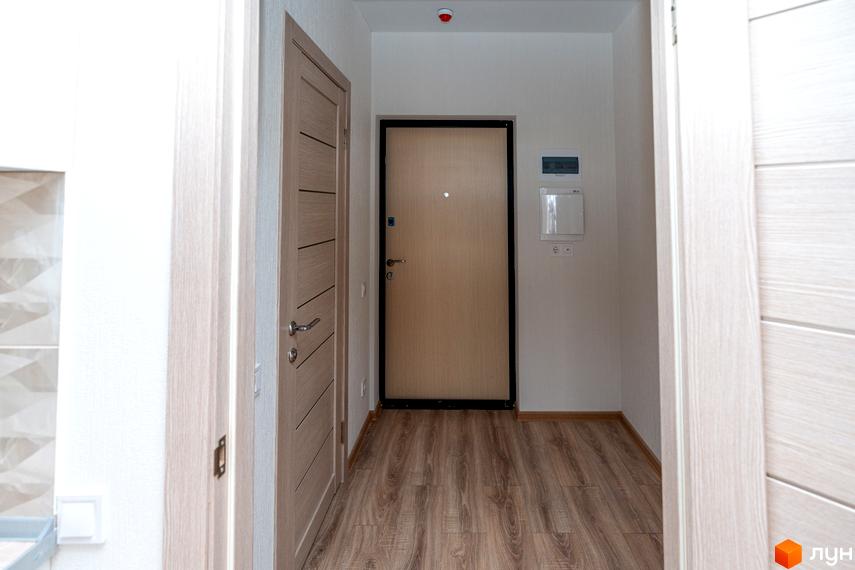 Передпокій у новобудові ARTVILLE з двома дверима та підлогою з ламінату. Білі стіни та стеля з пожежним сповіщувачем.