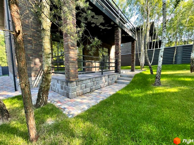 Зображення будинку в Котеджному містечку Elegant House. Навколо будинку зелений газон та дерева.