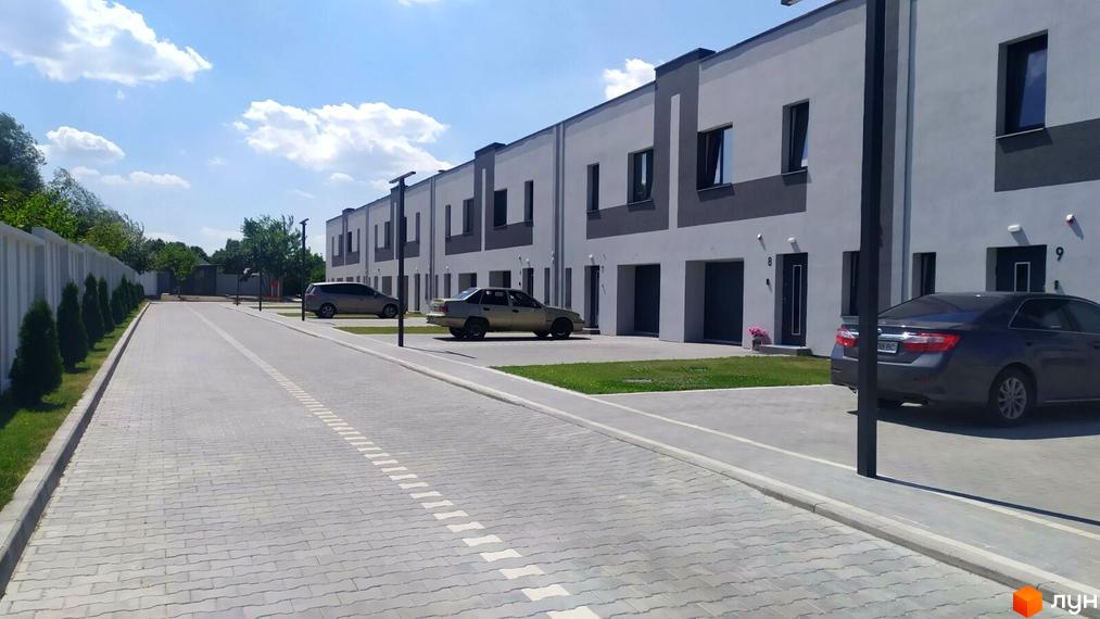 Таунхаус „Ефективний“: Ряди будинків з біло-сірими фасадами та гаражами. Прибудинкова територія з газоном та деревами.