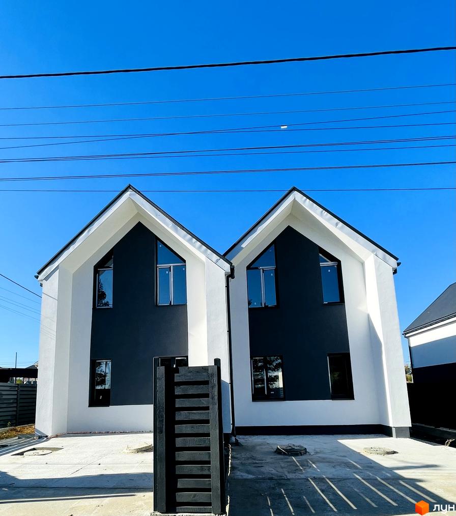 Дуплекси „На Зоряному“: біло-темні фасади, двосхилі дахи, трикутне скління. Попереду — бетонне подвір'я та чорна огорожа.