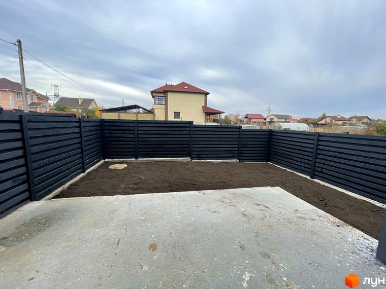 Огороджена територія з чорним парканом та доглянутою землею біля будинку. Дуплекси „На Зоряному“ – це новий житловий комплекс з індивідуальною забудовою.